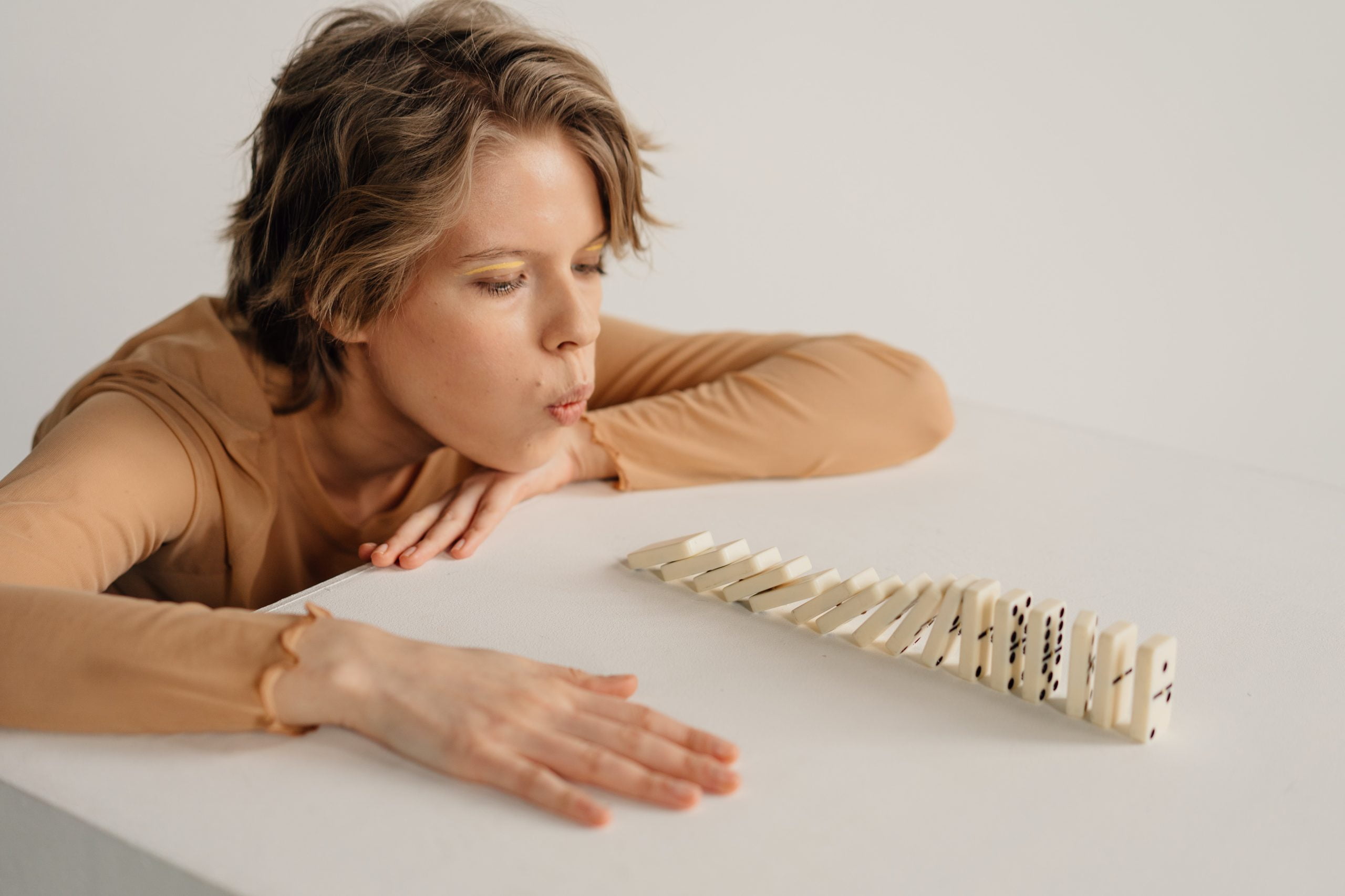 Woman blowing dominoes over into a cascade effect